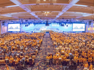 Shot from above and in front of huge crowd of people in a ballroom, wearing matching UFCW yellow shirts.