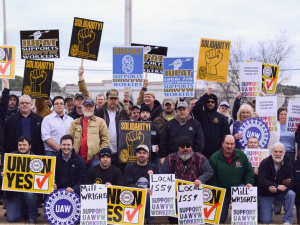 A crowd with signs saying "Millwrights Local 1554 support UAWVW workers," "IUPAT Local 226 supports UAWVW workers," "Solidarity," "Union Yes," "Ver.di," "UAW"