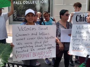 Voyant Beauty workers demonstrate in front of a Victoria's Secret store in Chicago, holding signs that read: "Victoria's Secret: Creams and lotions won't cover this injustice. We were fired for complaining about being treated as sexual objects! Voyant Beauty has got to go!" and "Victoria's Secret: More than creams and lotions we want dignity and respect! Cancel Voyant Beauty's contract now!"