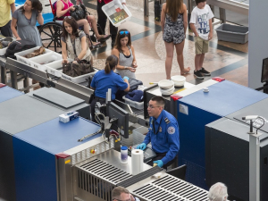 TSA workers are shown screening bags and scanning passengers at an airport