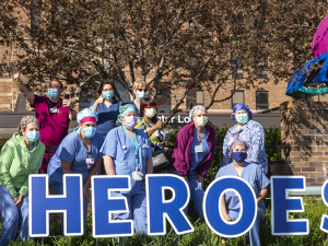 Medial personnel gathered outside in back of a sign that says "Heroes."