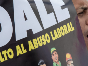 A man yells while holding a sign saying DALE ‘Alto Al Abuso Laboral’ (DALE stop workplace abuses)