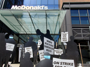 black silhouette cutouts representing workers on trike in front of mcdonald's