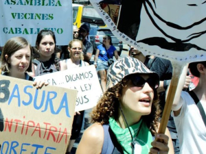 Several people with banners in Spanish march towards the camera’s right