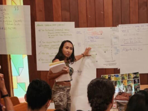 Woman leads organizing meeting from front of room.