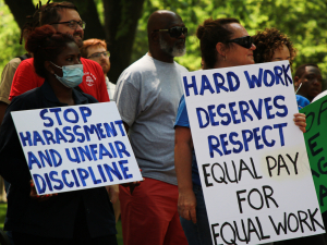 Housekeepers at the University of Pennsylvania rally holding signs that say "Hard work deserves respect: equal pay for equal work."