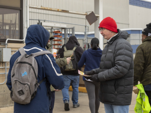 Candidate Shawn Fain passes out leaflets to several workers entering parts plant