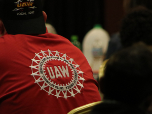 Back of man in red UAW shirt seated at event.