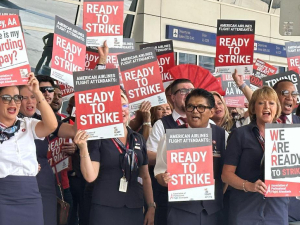 Dozens of men and women of various ethnicities wearing dark blue flight attendant uniforms hold signs saying “Ready to Strike”