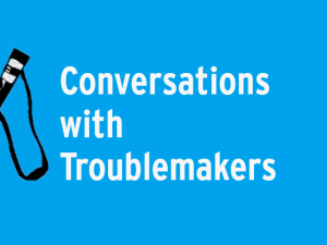 Black slingshot on blue background with text "Conversations with Troublemakers"