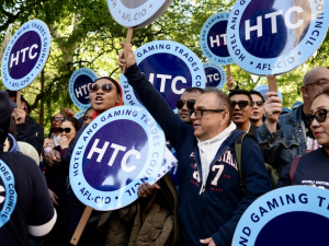 Several people chant with round Hotel Trades Council signs.