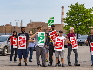 GM strikers picketing on the road holding signs.