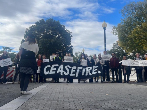 A group of people hold a black banner that says CEASEFIRE.