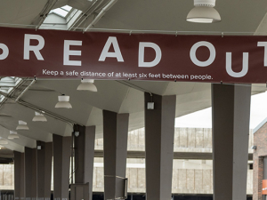 SPREAD OUT written on a sign above a road with pillars in the background.