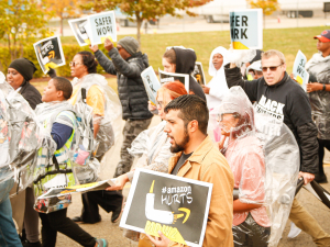 Amazon workers march holding signs that say higher wages. 