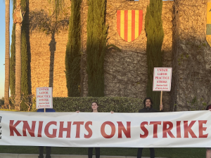 Strikers stand in front of Medieval Times holding a banner that reads "Knights on Strike."