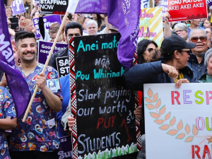 Workers rally holding colorful banners and signs.