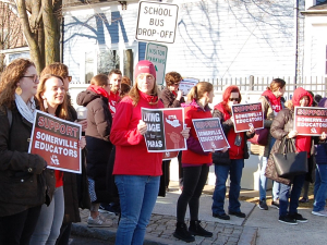 A crowd holding signs saying Support Somerville Educators and Living Wage for Paras