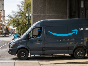 Amazon van exiting a building, about to turn onto a city street, with pedestrian crossing in front