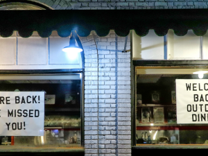 Signs in shop windows: "WE'RE BACK! WE MISSED YOU! WELCOME BACK OUTDOOR DINING"