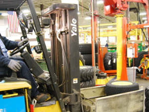 A worker drives a forklift inside a John Deere plant