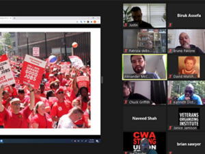 Zoom display shows a photo from Verizon strike (sea of red shirts) on the left; on the right, thumbnails of 18 participants in the call