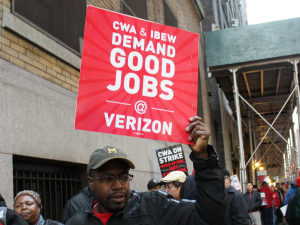 A striking worker holds a sign saying "CWA and IBEW Demand Good Jobs at Verizon" during the 2016 Verizon strike.