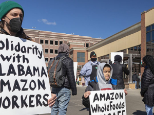 Adult and boy with signs in front of Whole Foods supporting Alabama Amazon workers attempting to unionize.