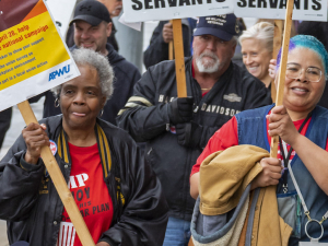 Postal workers march with signs about working conditions.