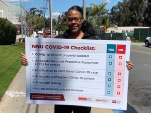 A nurse holds a sign showing "NNU COVID-19 Checklist: patient properly isolated, adequate PPE for nurses, notification to staff about case, adequate staffing for patient, adequate testing, nurses properly placed on leave"