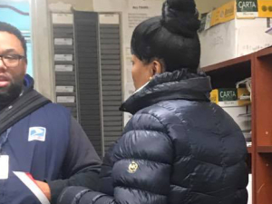 Two postal workers talking to each other inside an office.