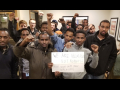 Amazon workers with fists raised gathered around a sign.