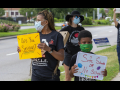 A woman holds a sign that says "Are you serious?", while her son holds a sign reading "Safe schools or no school."