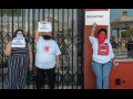 Three women hold signs saying "Food Not Rent" and "Cancel Rent" in English and Spanish.