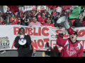 Oakland teachers marching down the street en masse with two bullhorns and a sign.