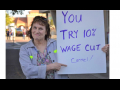 woman outdoors holds sign: "You try 10% wage cut Carmel!"