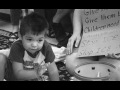 Child crouched in front of toys and a sign against ICE