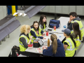 Workers in yellow vests sit around a lunch table at work.
