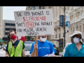 Three people marching against police brutality and for health care in Chicago with a sign