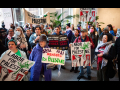 A group of forty cram into a building lobby with signs saying “Labor for Palestine”