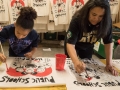 Two people painting signs that say "public schools are the heart of the community"