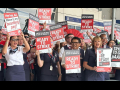 Dozens of men and women of various ethnicities wearing dark blue flight attendant uniforms hold signs saying “Ready to Strike”