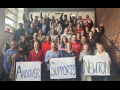 Two dozen teachers stand on stairs with signs saying ‘Andover Supports Newton’