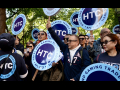 Several people chant with round Hotel Trades Council signs.
