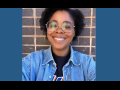 A smiling Black woman in round glasses and a jean jacket is shown