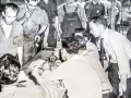 Workers—in their soiled work clothes—line up to vote at a table in a 1941 union election.