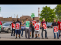 GM strikers picketing on the road holding signs.