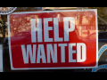 Help Wanted sign - background red, text white, in window of store