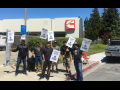 Members of Machinists Local 1546 stand in front of their workplace holding picket signs.