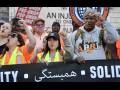 Members of the Laborers Union march during the May Day rally in New York City, behind a black banner that says solidarity in multiple languages, including Arabic.